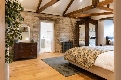 een slaapkamer met een bed en een stenen muur bij Trevidgeowe Farmhouse in Bodmin