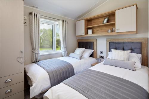 two beds in a bedroom with a window at Sycamore Farm Park in Burgh le Marsh