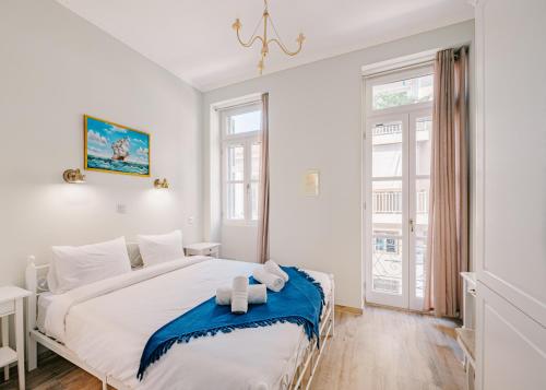 a white bedroom with a large bed with blue accents at Neapolis 1897 Boutique Luxury Rooms in Athens