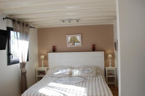 Schlafzimmer mit einem Bett mit gestreifter Tagesdecke in der Unterkunft Gîte Le Logis Vallat Bas in Fuveau