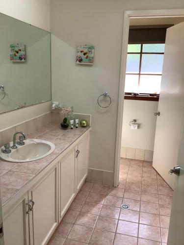 a bathroom with a sink and a mirror at Azalea Bed and Breakfast Hideaway in Tura Beach