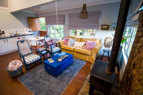 uma sala de estar com um sofá amarelo e cadeiras em Glen Islay Cottage Himeville em Himeville