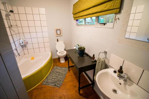 a bathroom with a tub and a toilet and a sink at Glen Islay Cottage Himeville in Himeville