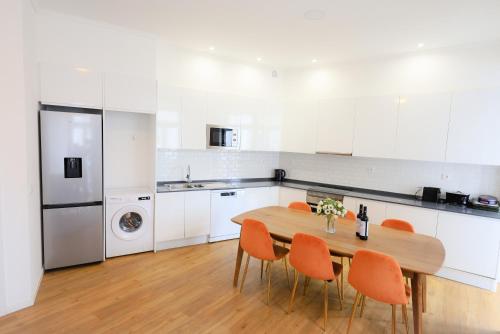 uma cozinha com uma mesa de madeira e cadeiras laranja em Lisboa Intendente 3Bedroom Apartment with Balcony em Lisboa