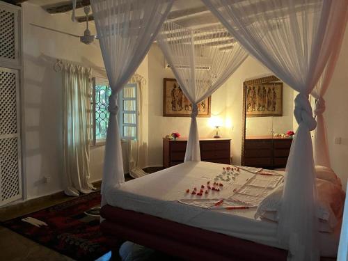 sypialnia z łóżkiem z baldachimem i białymi zasłonami w obiekcie Fulvia House w mieście Malindi