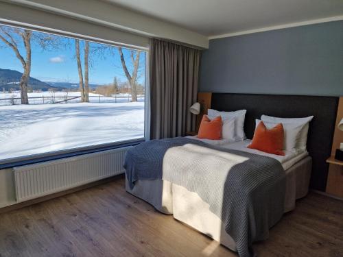 a bedroom with a bed with orange pillows and a large window at Granavolden Hotel & Gjæstgiveri in Gran