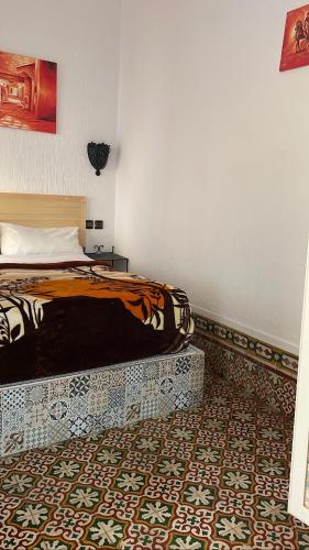 a bedroom with a bed and a patterned floor at Riad chez brahim in Essaouira