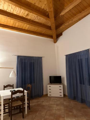 a dining room with a table and a tv and blue curtains at Cartari Apartment in Palermo