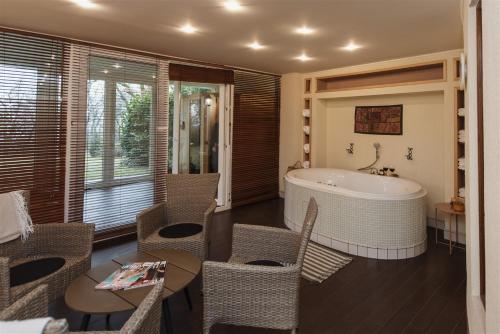 La salle de bains est pourvue d'une baignoire, d'une table et de chaises. dans l'établissement Hilltop Wellness Villa-big garden, sauna, hot tube, à Pécs
