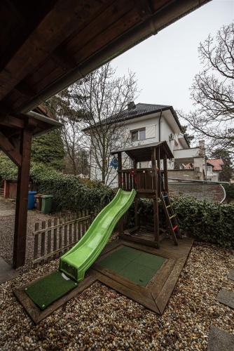 a playground with a green slide and a house at Hilltop Wellness Villa-big garden, sauna, hot tube in Pécs