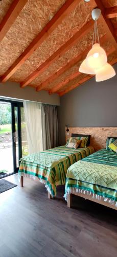 a bedroom with two beds and a large window at Poço e Meio - Padel & Pool in Santiago da Guarda