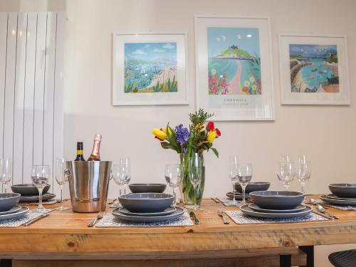 a table with plates and glasses and a vase of flowers at Pickney House in Looe