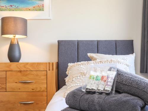 a bedroom with a bed with a wooden dresser and a lamp at Pickney House in Looe