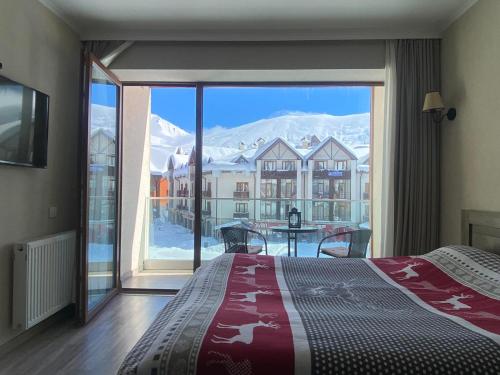 a bedroom with a bed and a large window with a view at New Gudauri Alpen Apartments in Gudauri