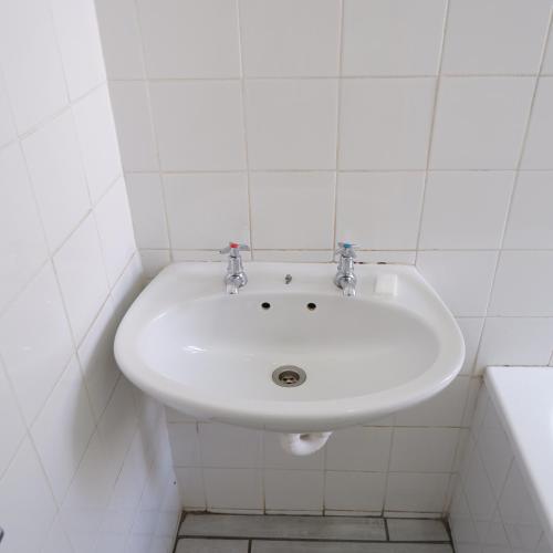 a white sink in a white tiled bathroom at The City Club in Cape Town