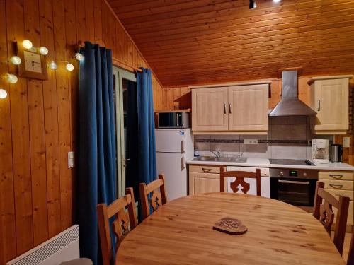 una cucina con tavolo in legno e frigorifero di Le repaire du Lynx a Bellefontaine
