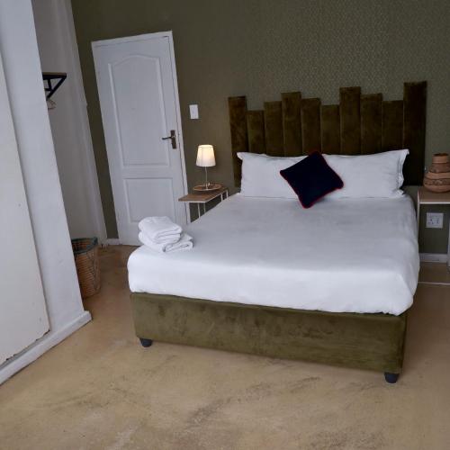 a bedroom with a large white bed with a blue pillow at The City Club in Cape Town