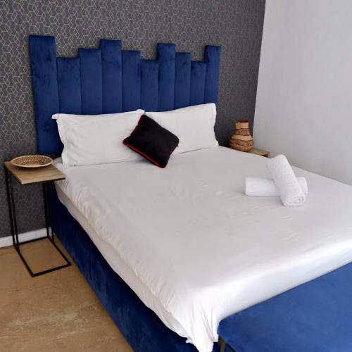a bed with a blue headboard and white sheets and pillows at The City Club in Cape Town