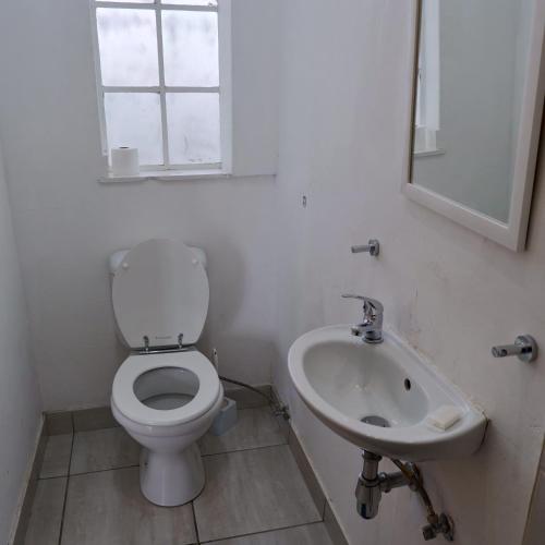 a white bathroom with a toilet and a sink at The City Club in Cape Town