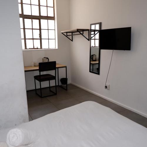 a room with a bed and a desk and a television at The City Club in Cape Town