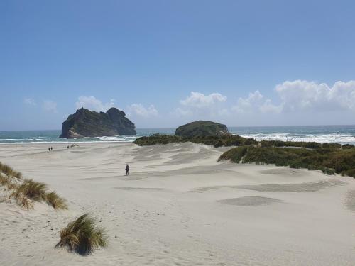 a person standing on a sandy beach near the ocean at Ratanui Lodge in Pohara