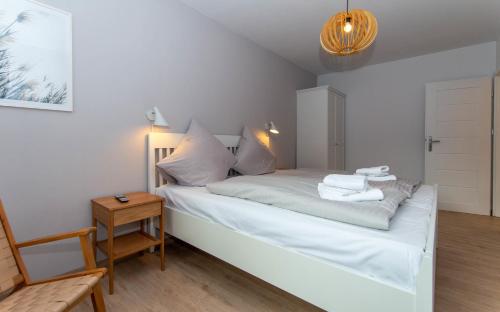 - une chambre avec un lit avec des draps blancs et une table dans l'établissement Nordsee-Flair, à Böhl