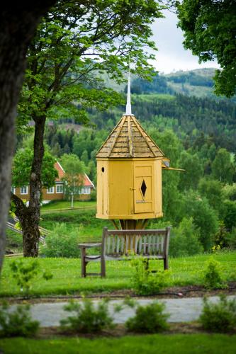 a yellow bird house sitting next to a bench at Granavolden Hotel & Gjæstgiveri in Gran