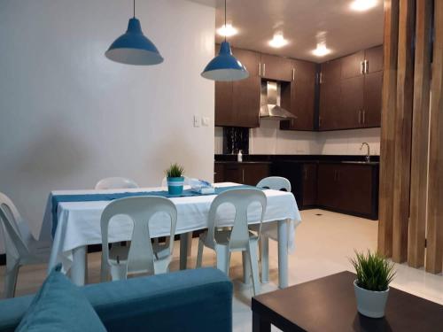 a dining room table with white chairs and a kitchen at GLC SUITES in Bislig