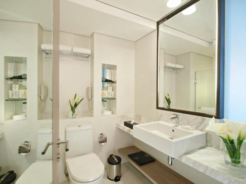 La salle de bains blanche est pourvue de toilettes et d'un lavabo. dans l'établissement Seda Abreeza Hotel, à Davao