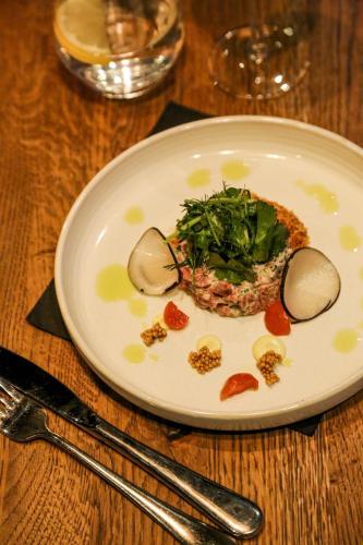 a white plate with food on a wooden table at Hotel Du Lac in Montriond