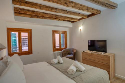 een slaapkamer met een bed, een tv en een stoel bij Ecco Suites Apartments in Venetië