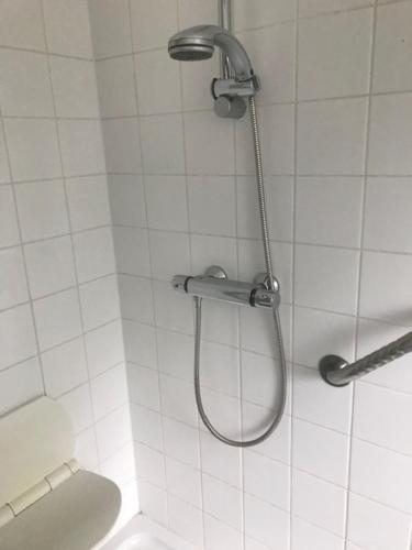 um chuveiro numa casa de banho com azulejos brancos e um WC. em Fokus PraktijkHuis em Dessel