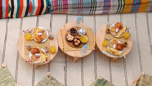 una mesa con tres platos de desayuno y zumo de naranja en Happy Marrakchy, en Marrakech