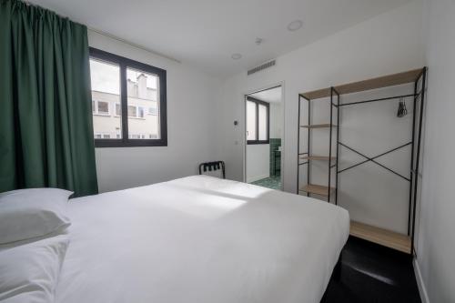 a bedroom with a white bed and a green curtain at Beau M Paris in Paris