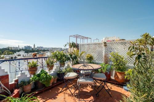 a balcony with a table and chairs and potted plants at DAR YAMNA Maison typique Kasbah de Tanger in Tangier