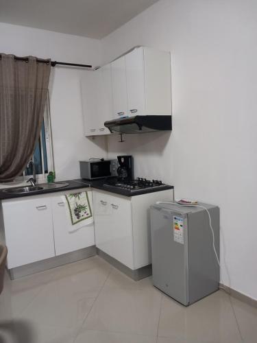 a small kitchen with white cabinets and a refrigerator at Casa Kyara T0 in Praia