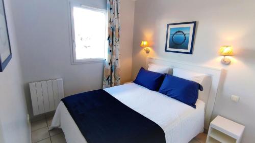 a bedroom with a bed with blue pillows and a window at Appartement 2 pièces dans résidence bord de mer aux Sables d'Olonne in Les Sables-d'Olonne