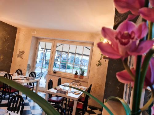 a restaurant with tables and a window and pink flowers at Albergo B&B Tenesi in Manerba del Garda
