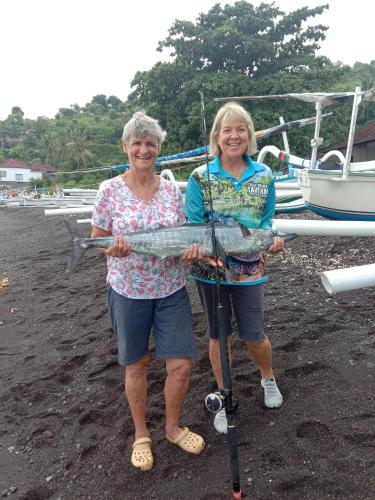 two older women holding a fish in their hands at Petit Boo Amed in Amed