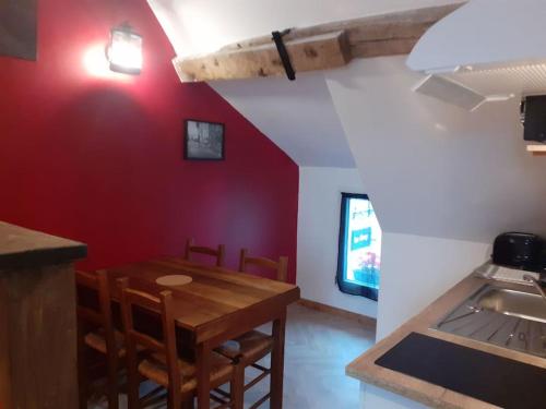 comedor con mesa de madera y pared roja en studio atypique et reposant, en Verdelot