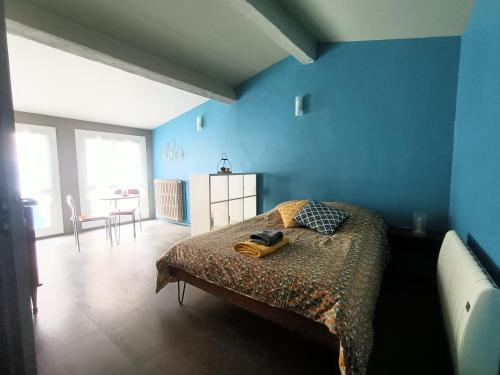 une chambre avec un lit avec un mur bleu dans l'établissement Studio Flow Libourne, à Libourne