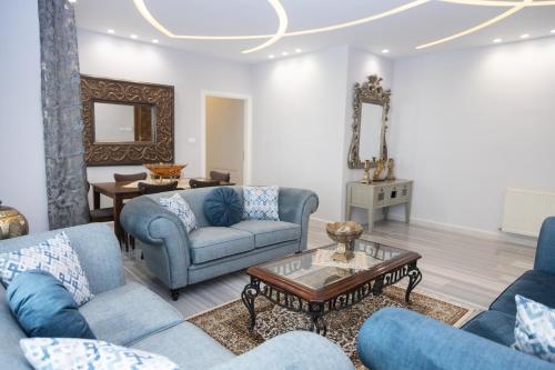 ein Wohnzimmer mit blauen Sofas und einem Tisch in der Unterkunft Luxury 3BR Apartment, Der Ghbar 165m2 in Amman