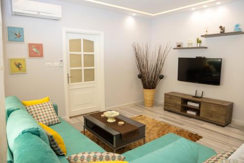 ein Wohnzimmer mit einem blauen Sofa und einem TV in der Unterkunft Luxury 3BR Apartment, Der Ghbar 165m2 in Amman
