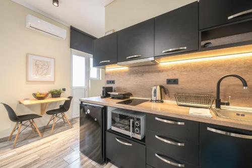 una cocina con armarios negros, fregadero y mesa en Petralona Stylish Penthouse, en Atenas