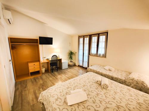 a hotel room with two beds and a desk at Albergo B&B Tenesi in Manerba del Garda