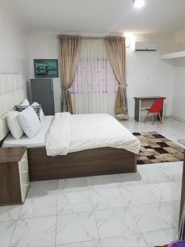a bedroom with a large bed and a table at Andrea’s Home in Abuja