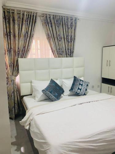 a bedroom with a white bed with pillows and a window at Andrea’s Home in Abuja