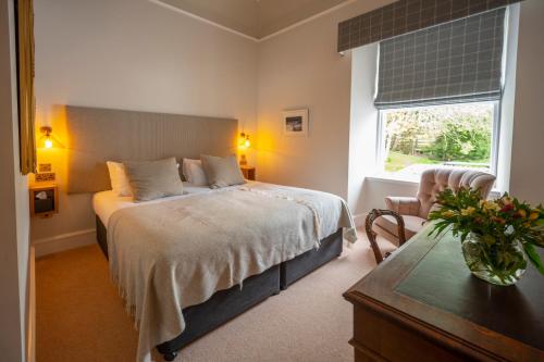Saplinbrae Hotel and Lodges في Mintlaw: غرفة نوم بسرير كبير ونافذة
