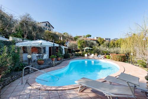 a swimming pool with chairs and an umbrella at Villa Renetta with Swimming pool and Jacuzzi and parking in Rapallo