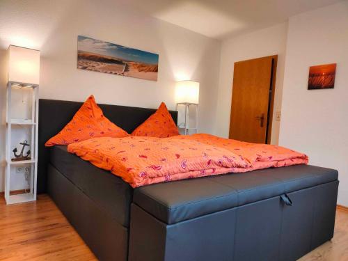 una cama con almohadas naranjas en una habitación en Ferienwohnung Leezdorf, en Leezdorf